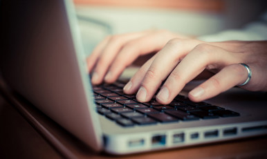 Två händer skriver på en laptop.